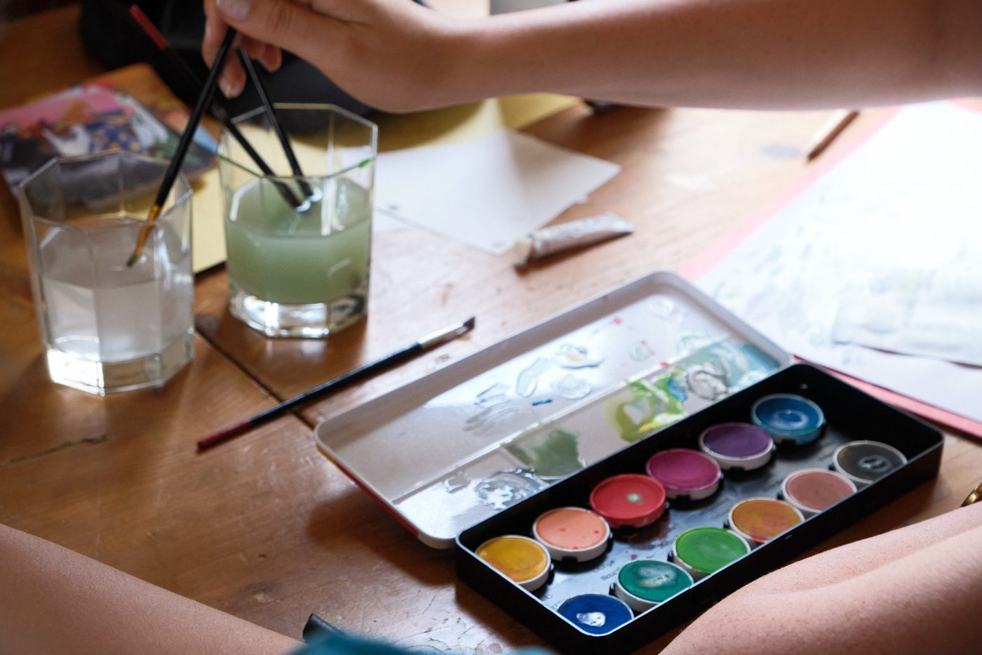 A watercolour set and brush glasses on the workshop table