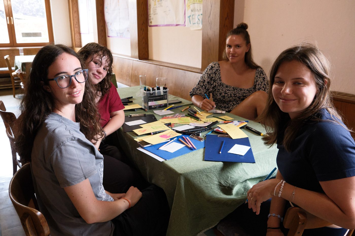Four participants smiling at a table covered in drawings and markers