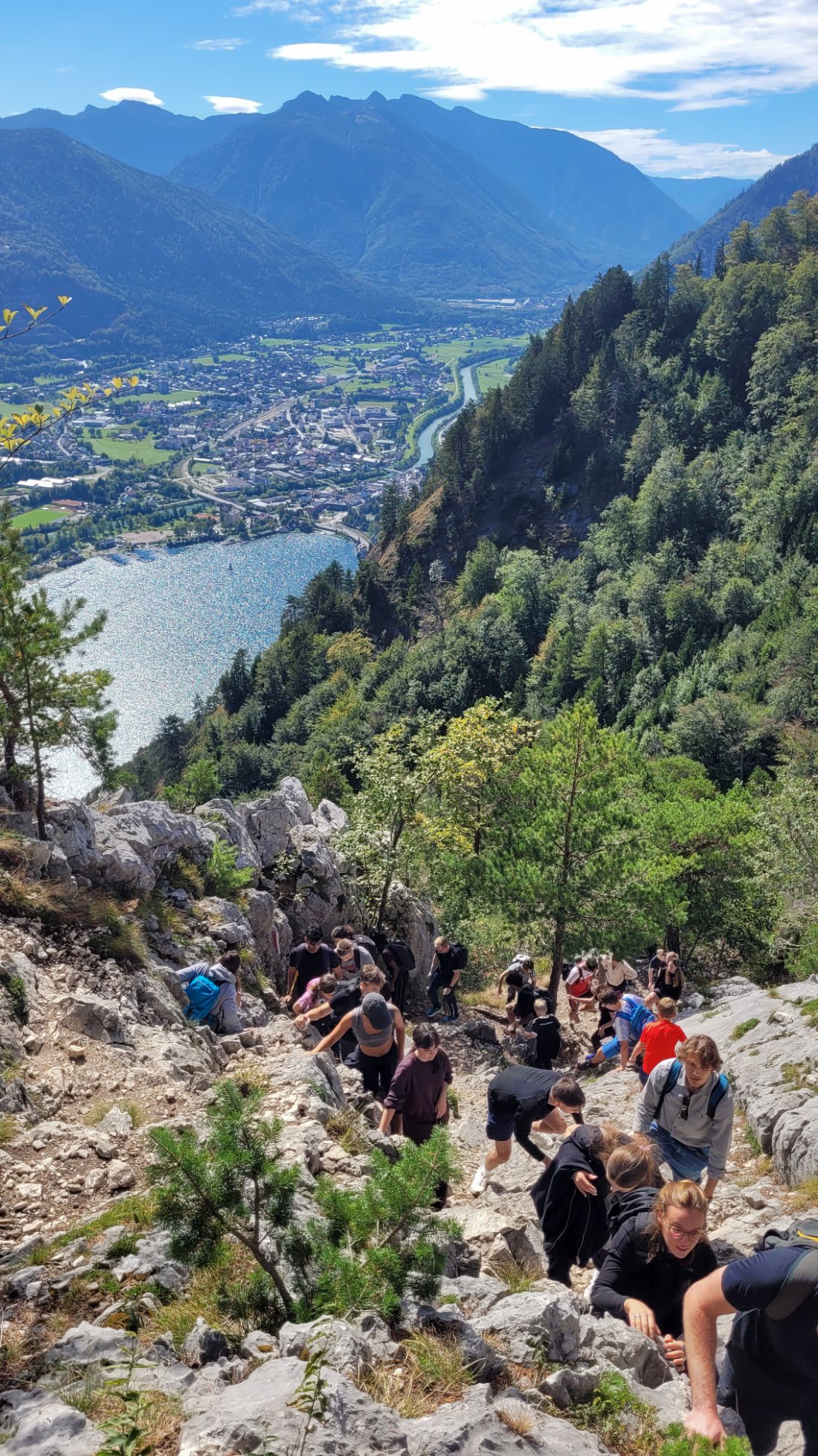 The group scrambling up rocks, with the lake and town far below